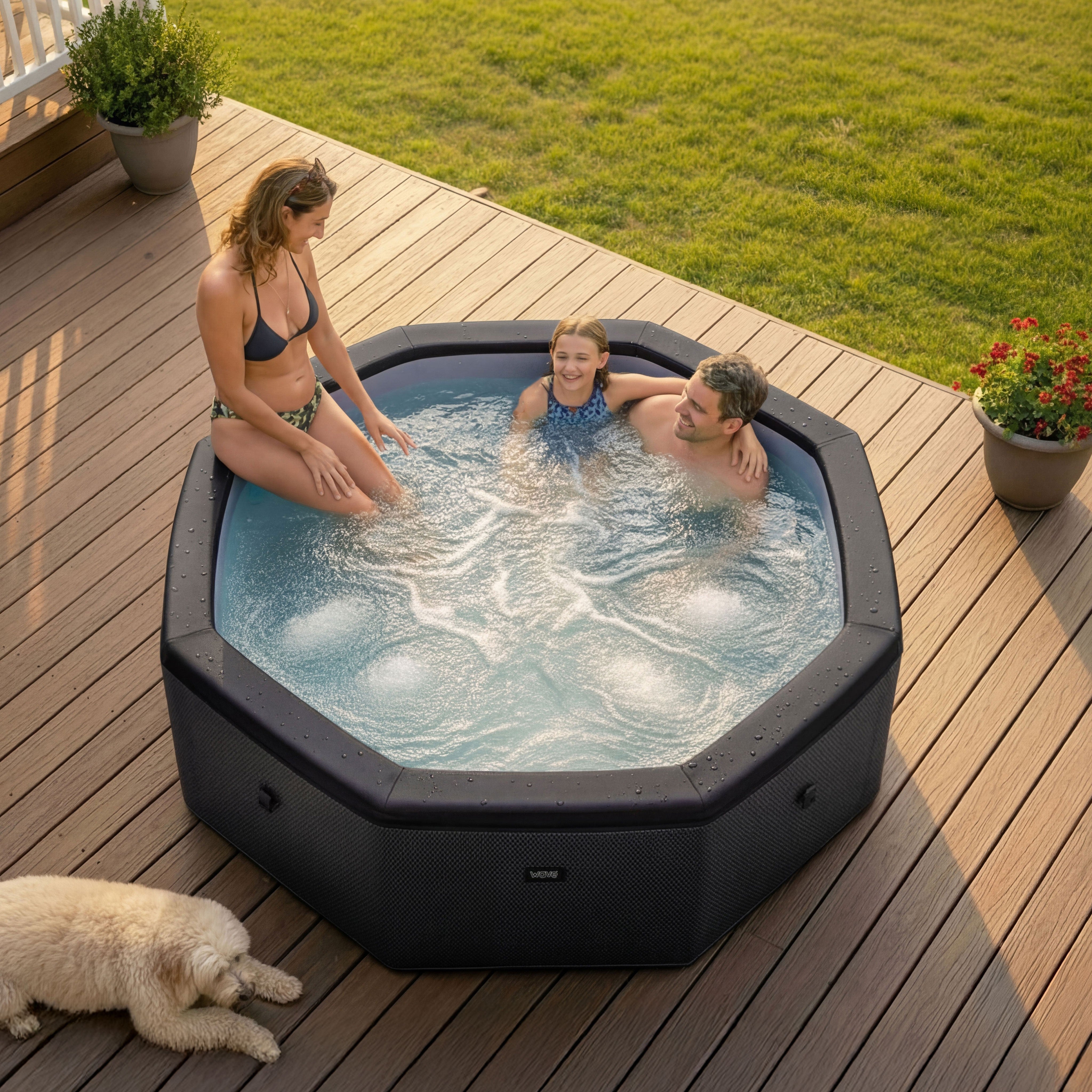 People enjoying a Wave Como hot tub on a wooden deck with a dog nearby