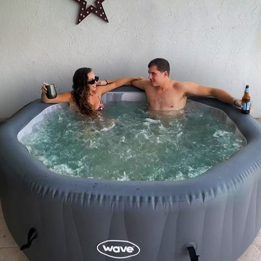 Couple relaxing with drinks in a grey Wave Aegean hot tub